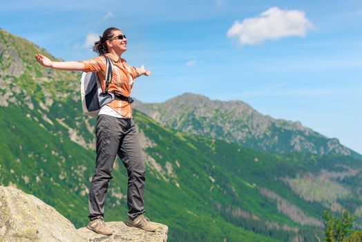 happy woman conquered a high mountain with a backpack enjoys freedom