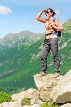 a tourist on the edge of the cliff enjoys the beautiful scenery of the mountains