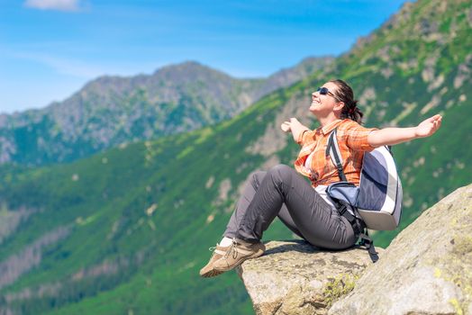 portrait of a happy tourist sitting on a mountain and enjoying freedom