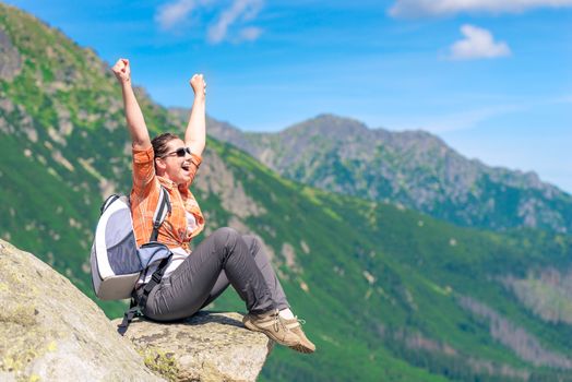 portrait of a successful tourist, sitting on the mountain and enjoying freedom