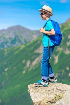portrait of a young traveler with a backpack high in the mountains on a rock