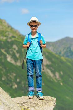 portrait of a small traveler with a backpack in the background of the mountains