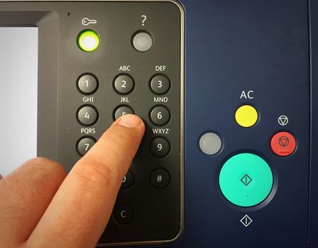 human finger typing the numbered buttons of an office photo copier