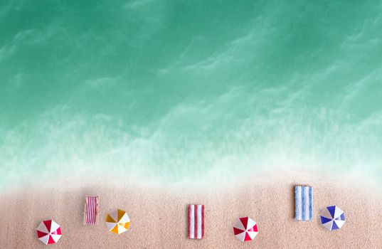 Aerial view of miniature beach parasols and towels by the sea