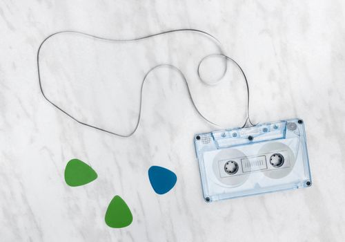 Blue audio tape and guitar picks on marble background.