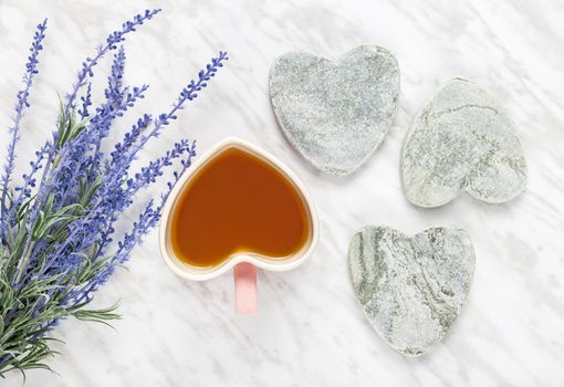 Cup of flavored tea and blue lavender. Love for tea. Flat lay composition with heart-shaped mug and stone hearts.