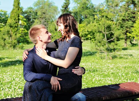 A loving couple flirting sitting on a bench in a city park.