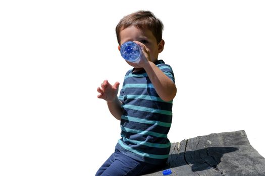 Thirsty little boy sitting on a wooden bench and drinking water.