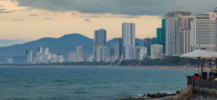 Nha Trang, Vietnam, Asia June 6 2018. Vietnamese holiday resort beach front skyline scene with skyscraper hotels and apartment blocks. On the south china sea with rugged mountain landscape in the background and tourists enjoying the beautiful golden beach.