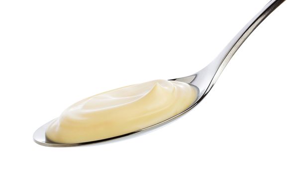 Sour cream in spoon isolated on white background with clipping path.