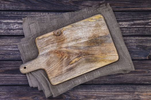 Cutting board on dark wooden table. Top view. Copy space