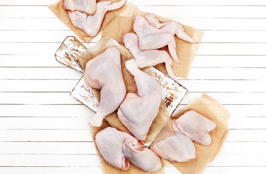 Raw chicken meat on cutting board on a white wooden background. Top view. Copy space