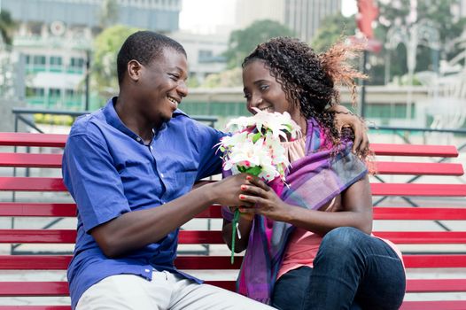 This young man gives a flower to a young woman he looks into her eyes with a beautiful smile