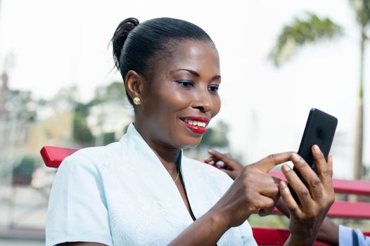 This young woman consults her phone with  smile on her face.