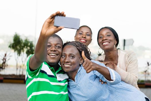 group of young people taking a picture with a mobile phone to mark their reunion.