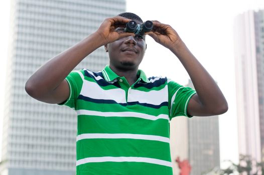 young businessman looks through binoculars to signify that he is looking for paths to succes.