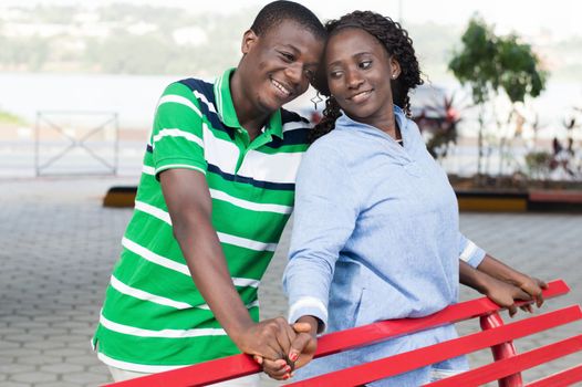 Young happy couple leaning against a bench relishing a good time in this park.