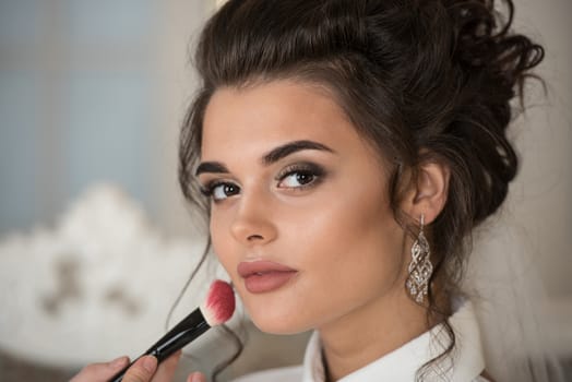 Artist applying blush to wedding make up for bride