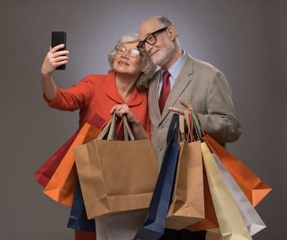 Happy couple taking selfie after shopping with many bags
