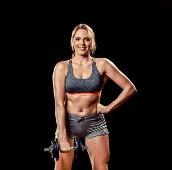 Beautiful muscular woman lifting dumbbell isolated on black background