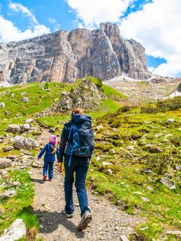 Mother and her daughter hiking in the mountains. Travellig adventre and active vacation with children. Dolomites, Italy.