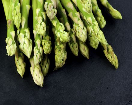 Heap of Fresh Asparagus Sprouts closeup on Black Slate background