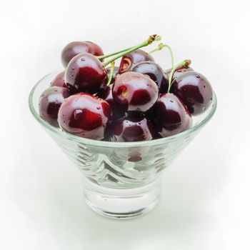 Glass conic vase with wet cherry berries isolated on white background