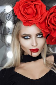 Lovely woman with blood spill on face wearing rose headgear and looking at camera while standing in studio