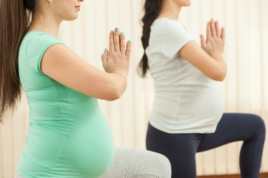 Beautiful pregnant women doing yoga in the gym