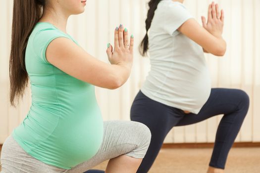 Beautiful pregnant women doing yoga in the gym