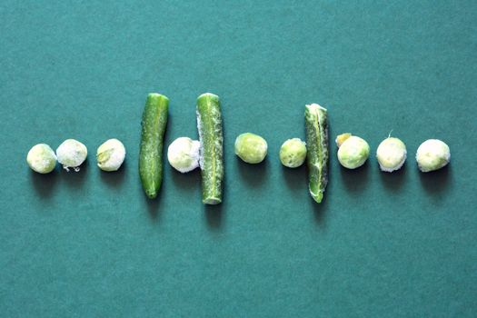 Frozen needle beans and pea in a row on green background