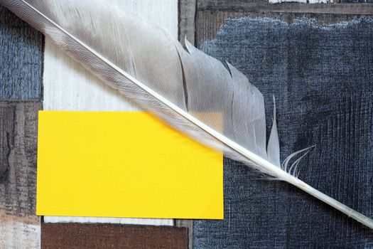 Vintage still life with quill pen near yellow blank paper