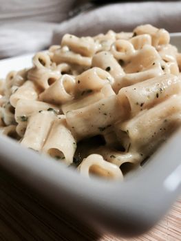 Tasty pasta with broccoli and chives on wooden board at home.