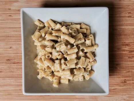 Delicious broccoli pasta in square plate on the wooden board at home. Food concept.