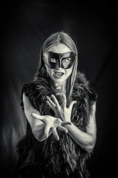 Woman in black mask performing in studio against black background