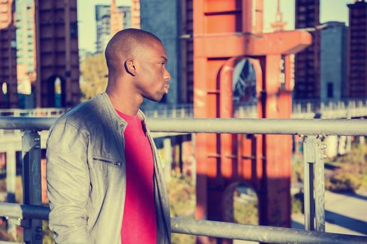 Portrait of a sexy young black man in urban environment wearing red shirt and grey leather jacket
