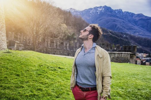 Attractive man outdoor in old European castle, in Switzerland. Athletic build, with tight t-shirt and sunglasses