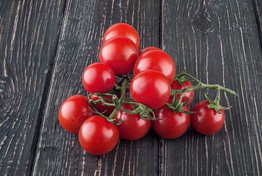 Two branches of cherry tomatoes. Dark wooden table. Blurred background.