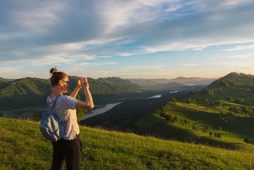 Woman taking photo on mobile phone at the mountain peak.