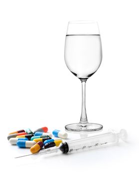 Glass of water  syringe and colorful pill and capsules on white background