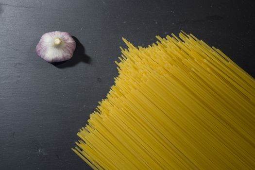 Macaroni and garlic on a black stone board