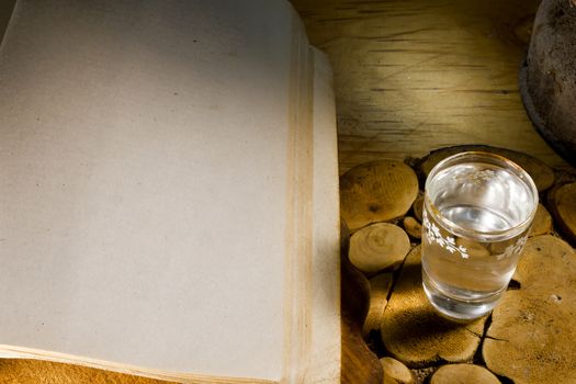 Glass of vodka and an ancient book on an old wooden table