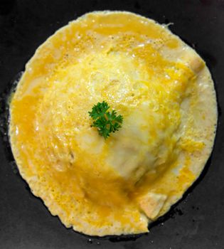 top view of rice with omelet on black dish.