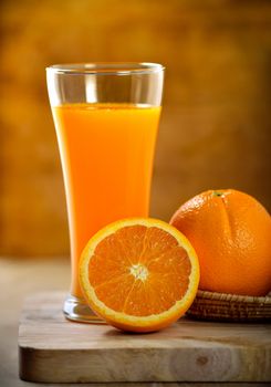 Orange juice glass and fresh oranges on wood