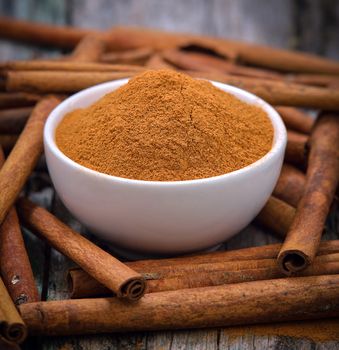 Cinnamon sticks and powder cinnamon in the bowl on table