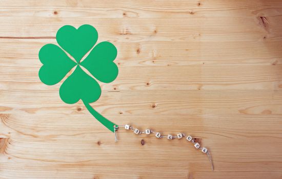 The german words for Good Luck and a cloverleaf on a cord on wood