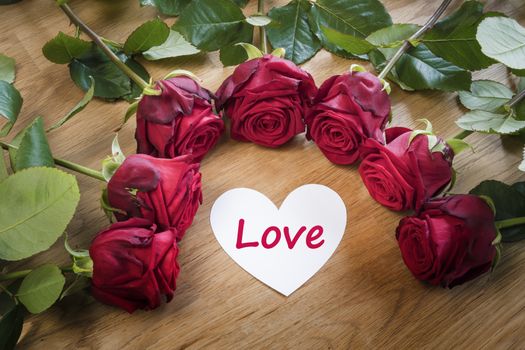 Red roses on a table with a white Love heart