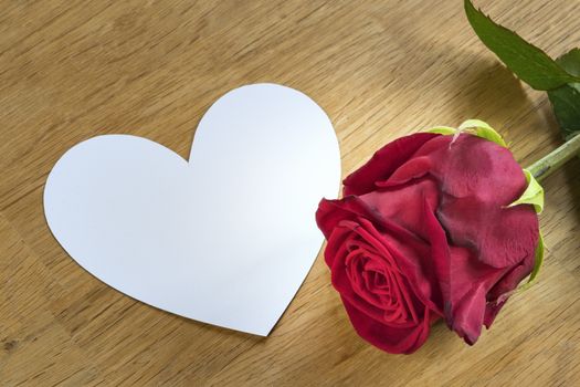 red rose on a table with white heart