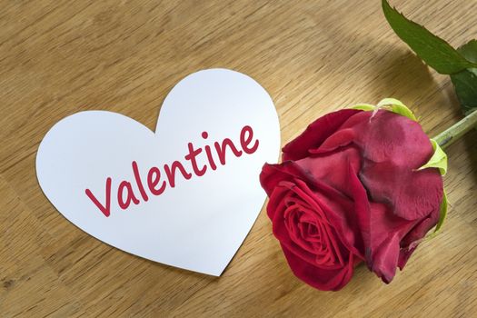 red rose on a table with white valentine heart