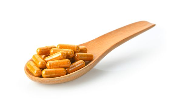 Turmeric Capsule in wood spoon on white background